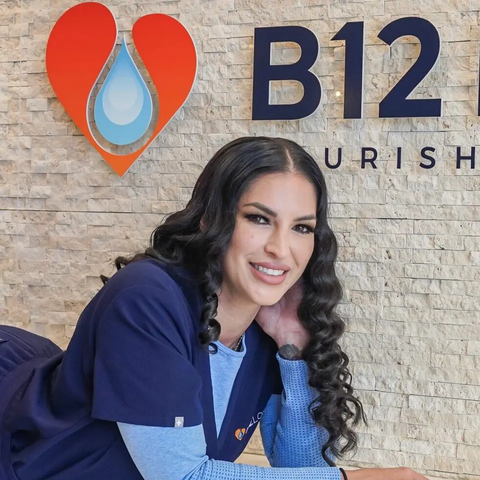 Victoria, a B12 LOVE Campbell team member, in front of the logo wall