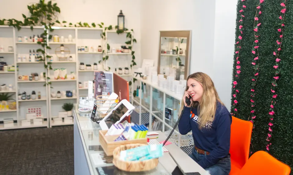 Staff member at the front desk with retail shelves at B12 LOVE Mill Valley