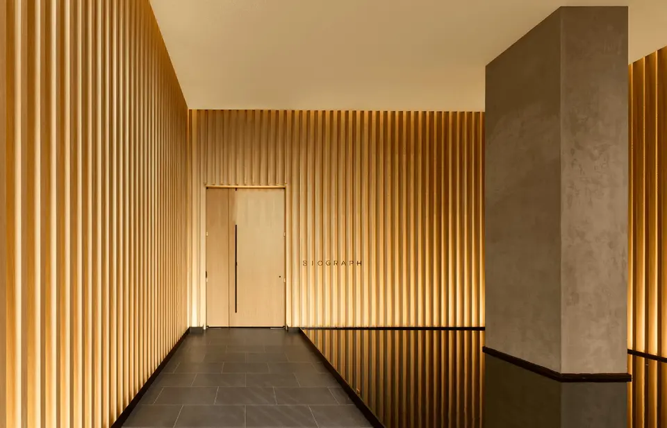 Corridor lined with backlit vertical wood slats at Biograph New York