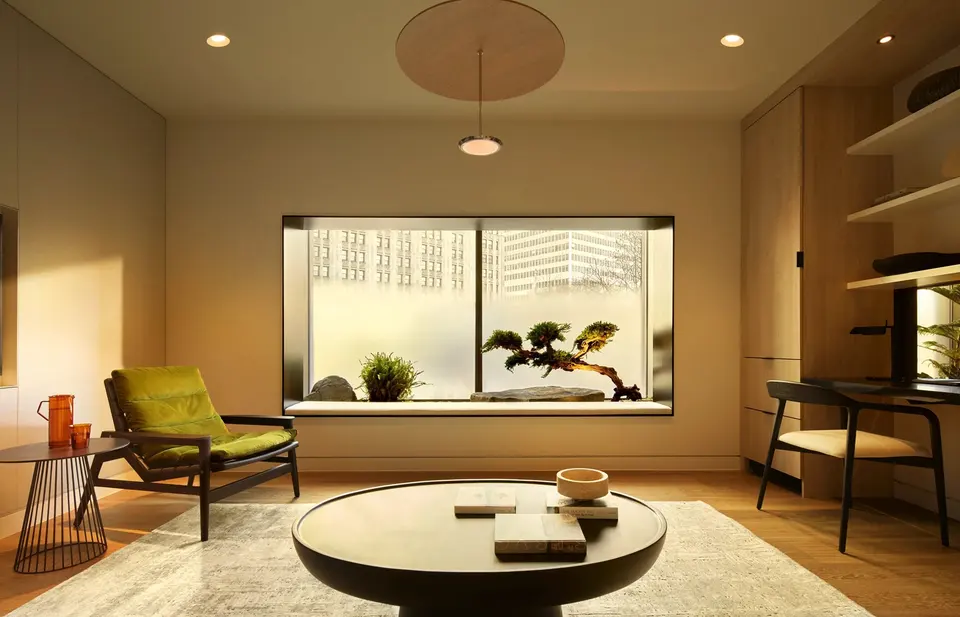 Warm-lit consultation lounge with armchair, round table and city-view window at Biograph New York