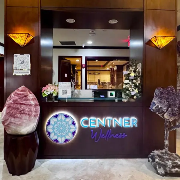 Entrance to Centner Wellness Brickell with backlit logo sign flanked by large crystal geodes