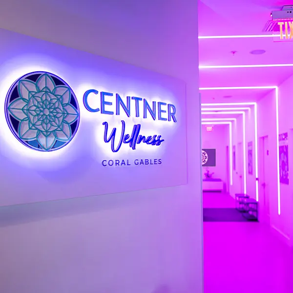 Illuminated Centner Wellness Coral Gables sign beside a pink-lit corridor