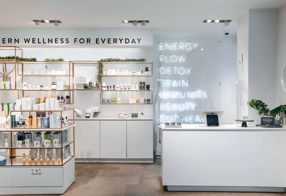 Checkout counter and product shelves beside a neon wall at Clean Market Midtown East