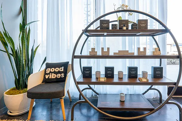 Round retail shelf of candles and wellness products beside a window at EvolvE