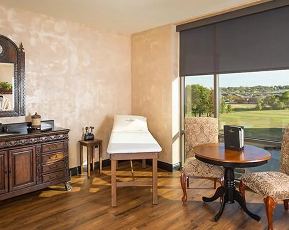 Private exam suite at Executive Medicine of Texas with an exam table, a small dining table and a large window