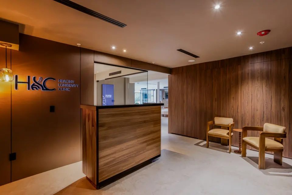 Reception desk with backlit Healthy Longevity Clinic sign and wood-panelled walls
