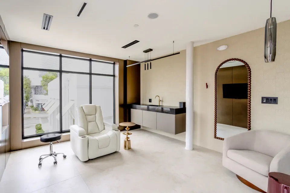 Bright treatment room with a white recliner, arched mirror and large windows at Healthy Longevity Clinic Miami