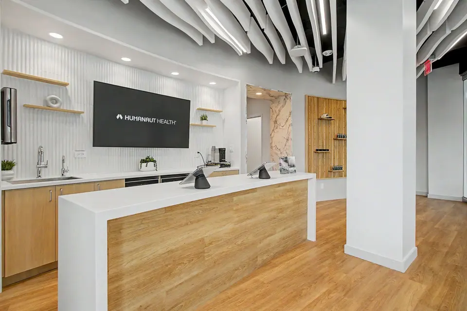 Reception desk with a Humanaut Health display screen beneath curved ceiling baffles