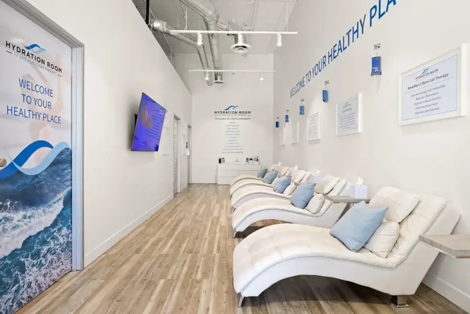 Row of white lounge chairs and welcome wall at Hydration Room Irvine
