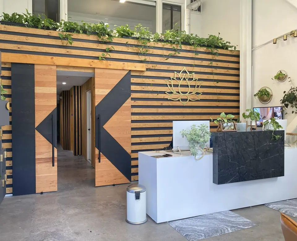 Reception desk and wood-slat wall with lotus logo at Kume Float
