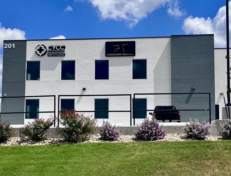 White building at 201 in Hutto with Longhorn Imaging signage on the facade and flowering shrubs out front