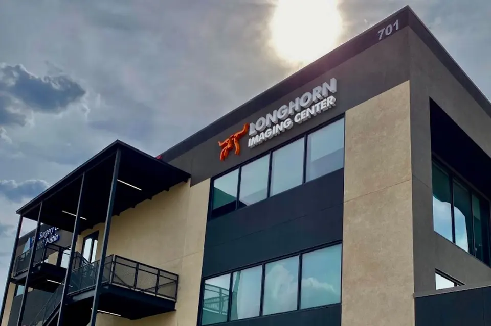 Corner of the building at 701 with a Longhorn Imaging Center sign and orange longhorn logo, Onion Creek