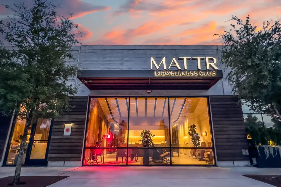 MATTR Bio Wellness Club entrance at dusk, with its illuminated sign above a glass-walled lobby