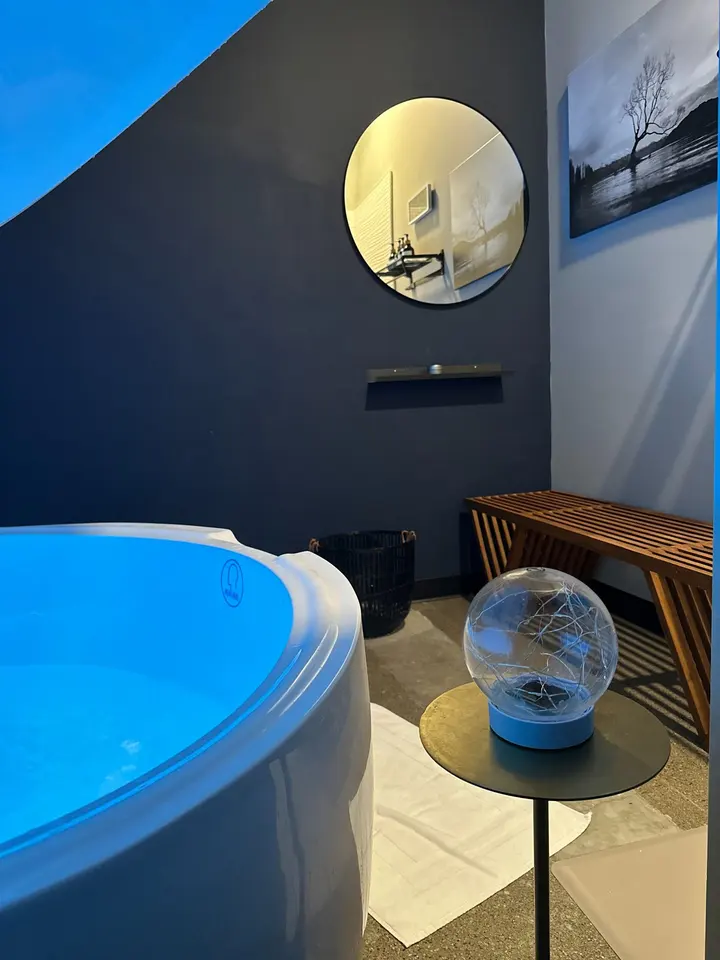 Float tub room with round mirror and bench at Newport Body Works