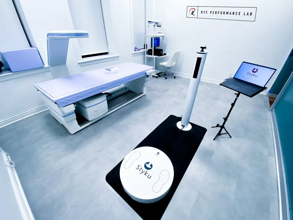 Body composition room with a DEXA scanner, 3D body scanner platform and NYC Performance Lab wall sign