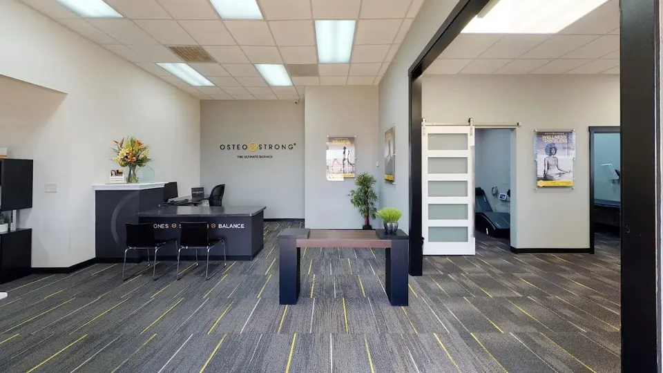 Lobby at OsteoStrong Carrollton with a front desk, seating and OsteoStrong lettering on the back wall