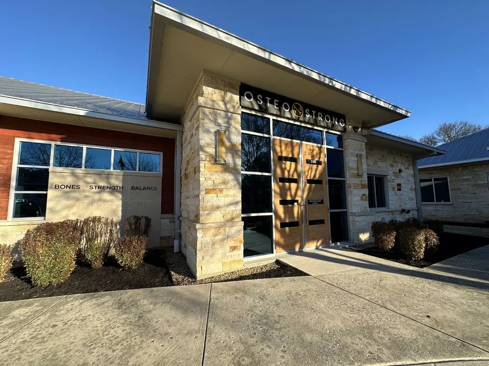 Stone-and-glass entrance of OsteoStrong McKinney Stonebridge with the OsteoStrong sign above the door