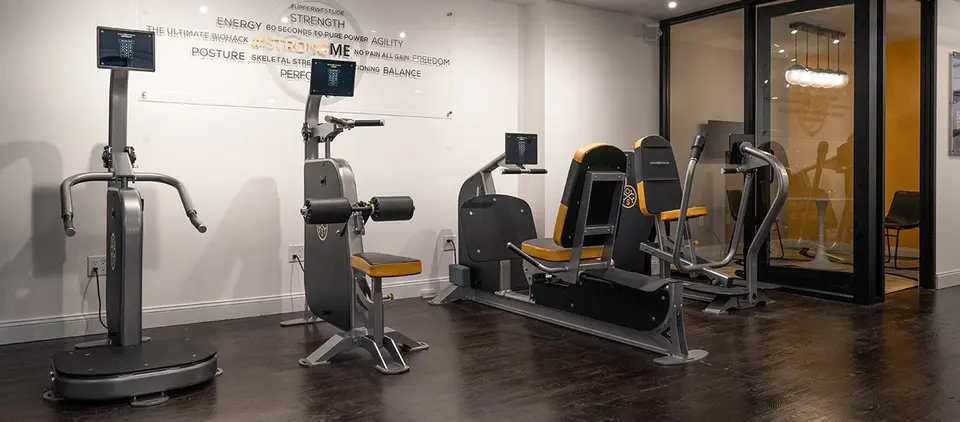 Row of OsteoStrong resistance machines on dark wood floor at OsteoStrong Upper West