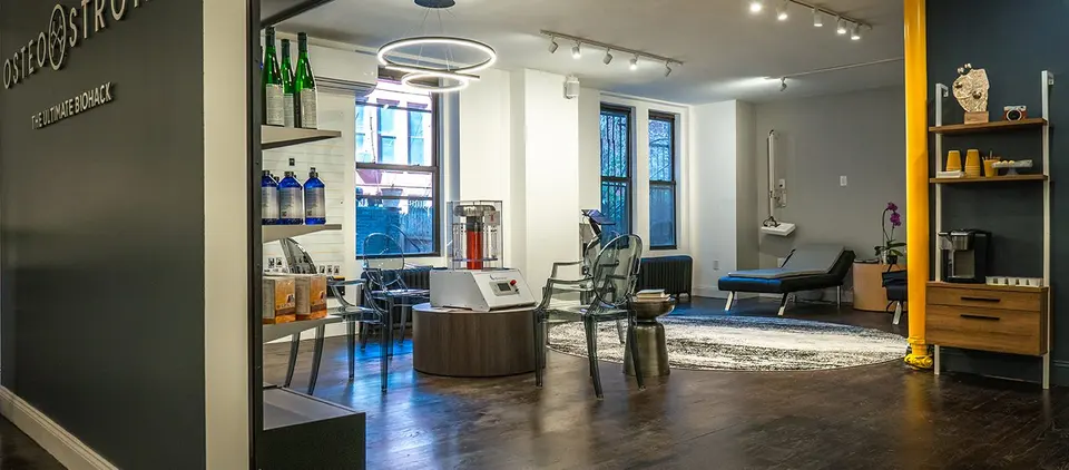 Lounge area with shelving, seating and a red-light device at OsteoStrong Upper West