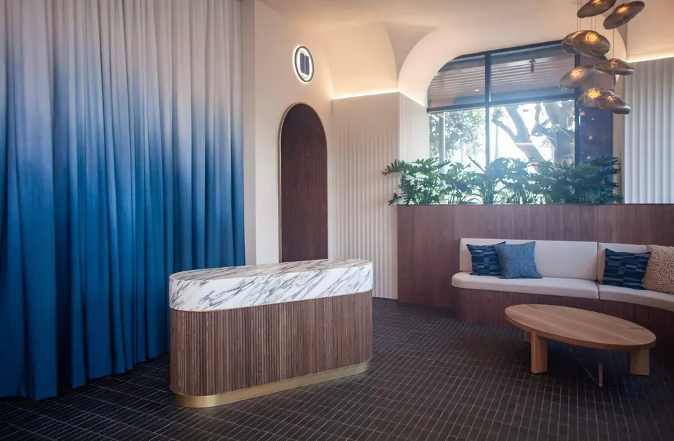 Reception desk and lounge seating with blue ombre curtains at Pause Studio Brentwood