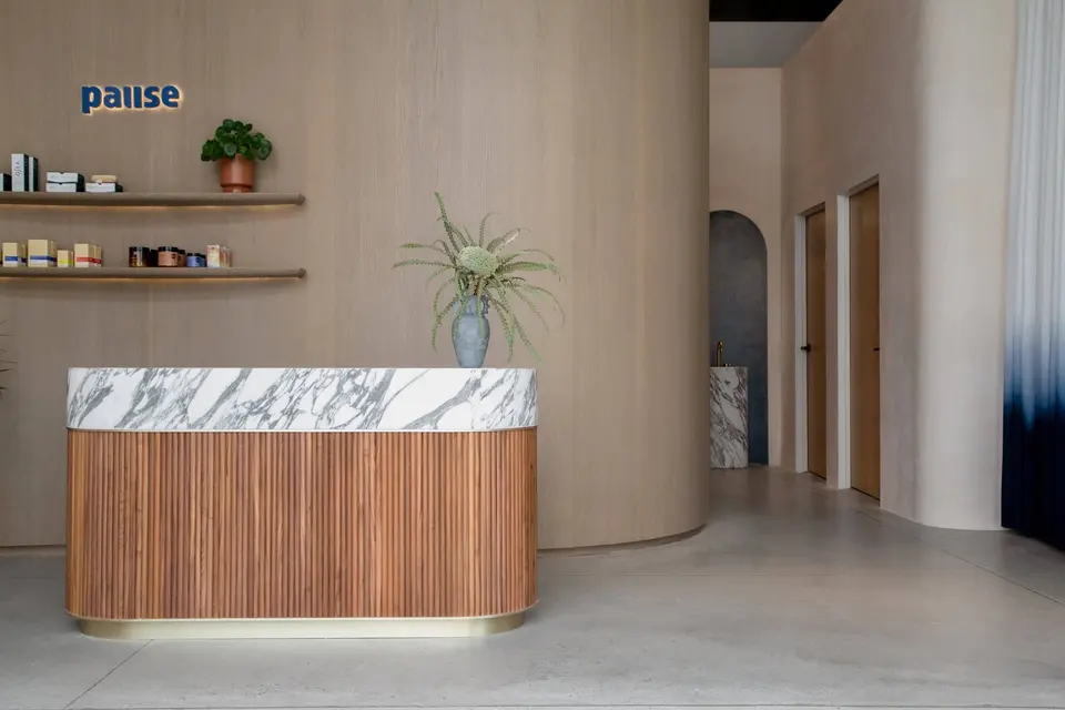 Wood-slat reception desk and retail shelf at Pause Studio South Bay