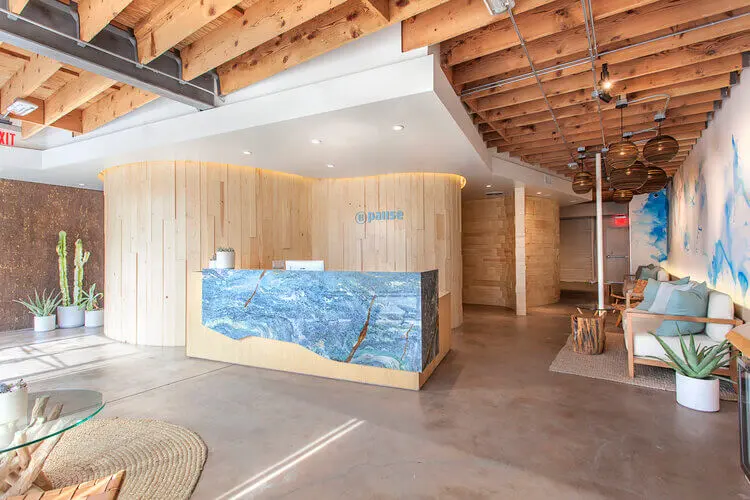 Lobby with blue stone reception desk and exposed wood ceiling at Pause Studio Venice