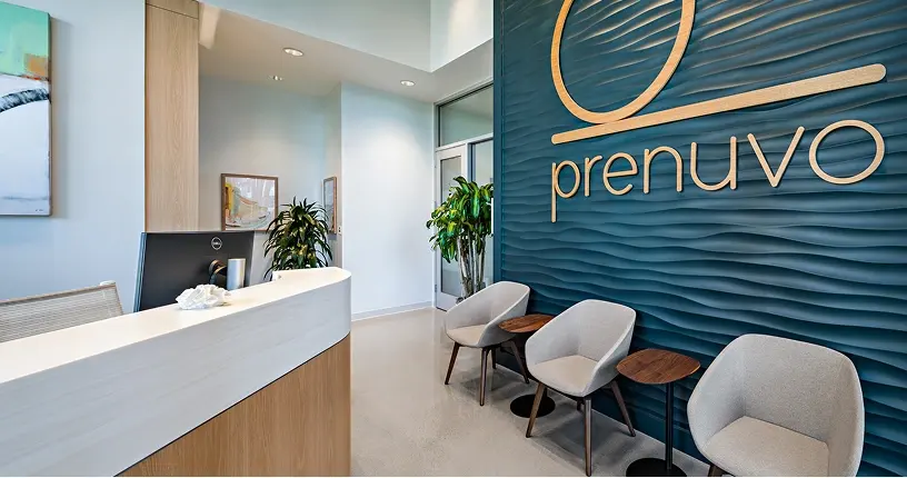Reception desk and waiting chairs in front of the Prenuvo wave wall in Irvine
