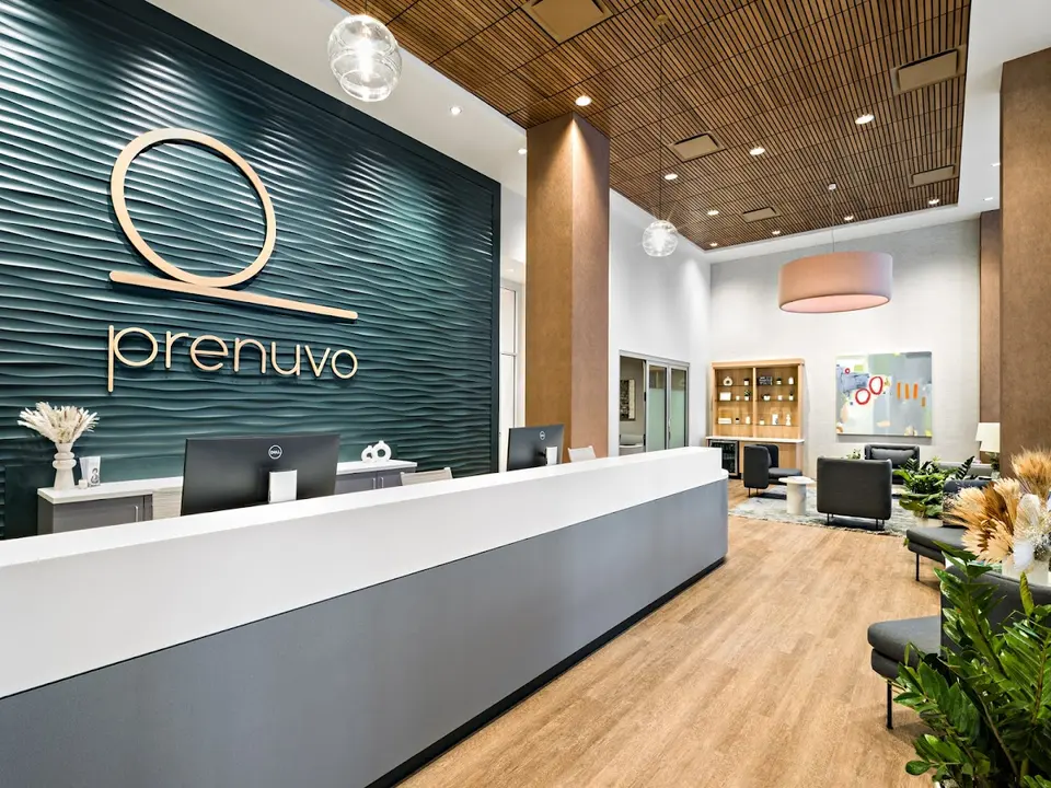 Reception desk in front of a teal wave wall with the Prenuvo logo at Prenuvo New York