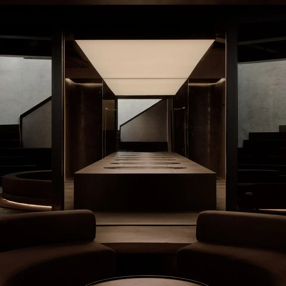 Dim lounge looking toward a long stone table under a glowing light panel at Remedy Place Soho