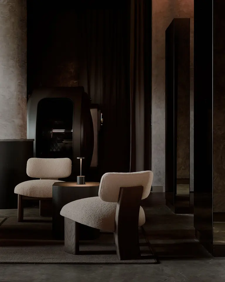 Two cream lounge chairs beside dark curtains and an arched treatment pod at Remedy Place Soho