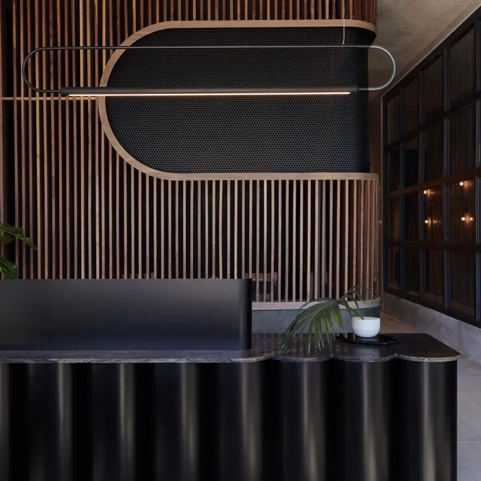 Curved black reception desk and wood-slat wall at Remedy Place West Hollywood