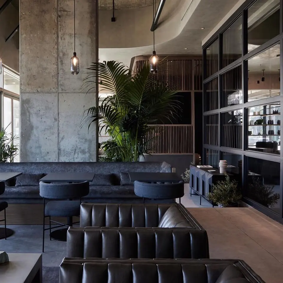 Lounge with leather banquettes, concrete columns and palms at Remedy Place West Hollywood