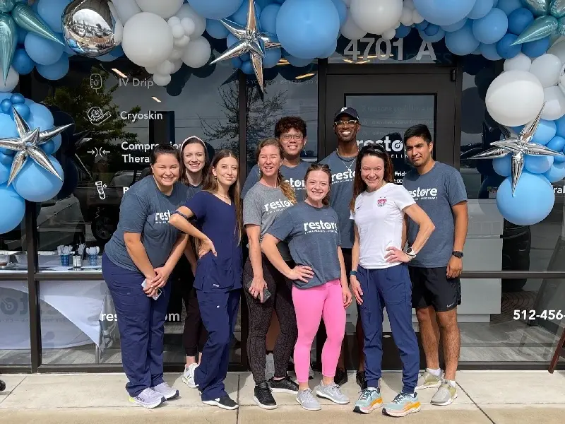 Restore Hyper Wellness Cedar Park team posing outside the studio entrance under a balloon arch