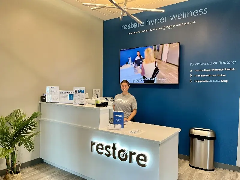 Staff member at the Restore reception desk in front of a blue feature wall in Westbury
