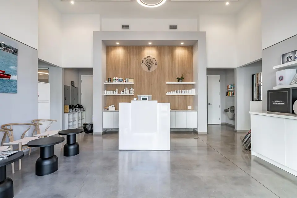 Bright reception with white desk, wood feature wall and product shelves at The Biohack Lab Fort Lauderdale