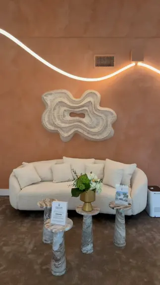Lounge with a curved cream sofa, sculptural wall art and neon light line at The Biohack Lab MiMo