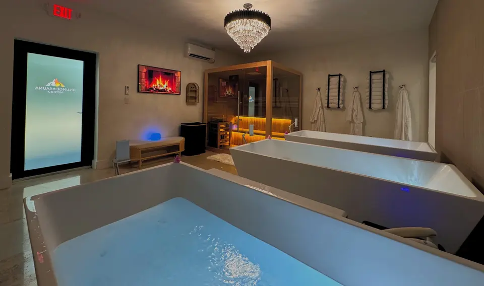 Cold plunge tubs under a crystal chandelier with a sauna cabin in the background at The Plunge & Sauna Method