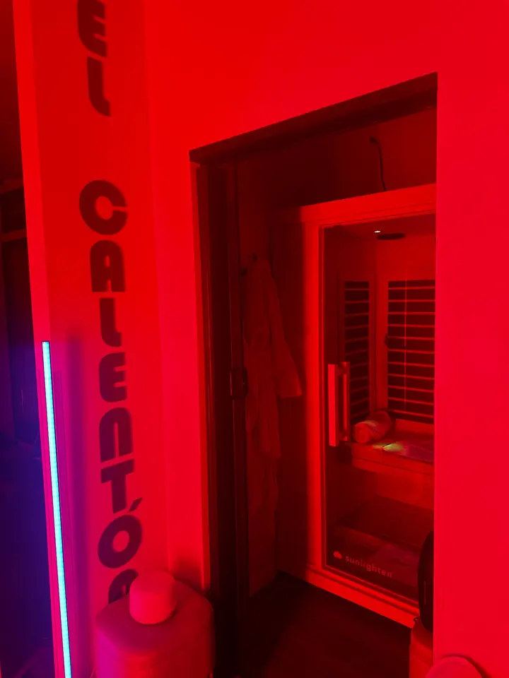 Red-lit infrared sauna room seen through an open doorway
